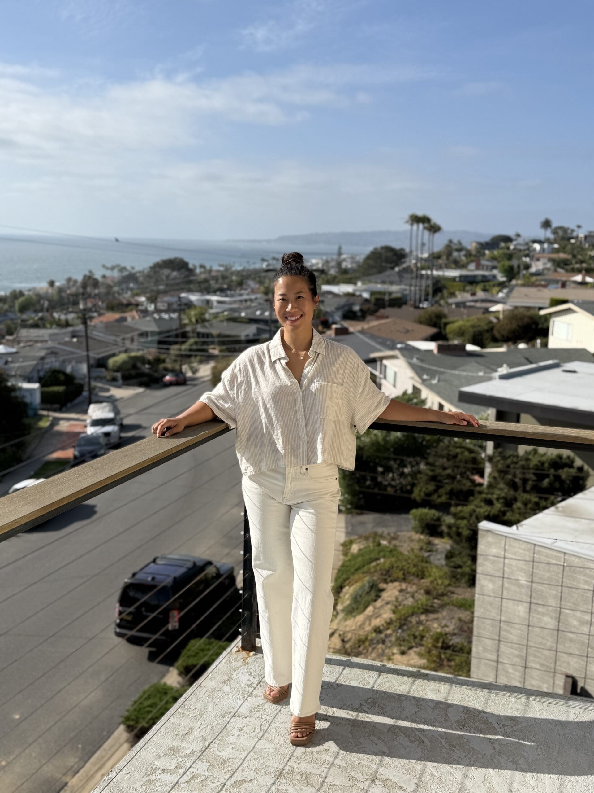 woman on a sunny deck in san diego overlooking the houses and ocean